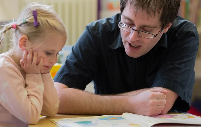 groups A child and an adult reading a book together